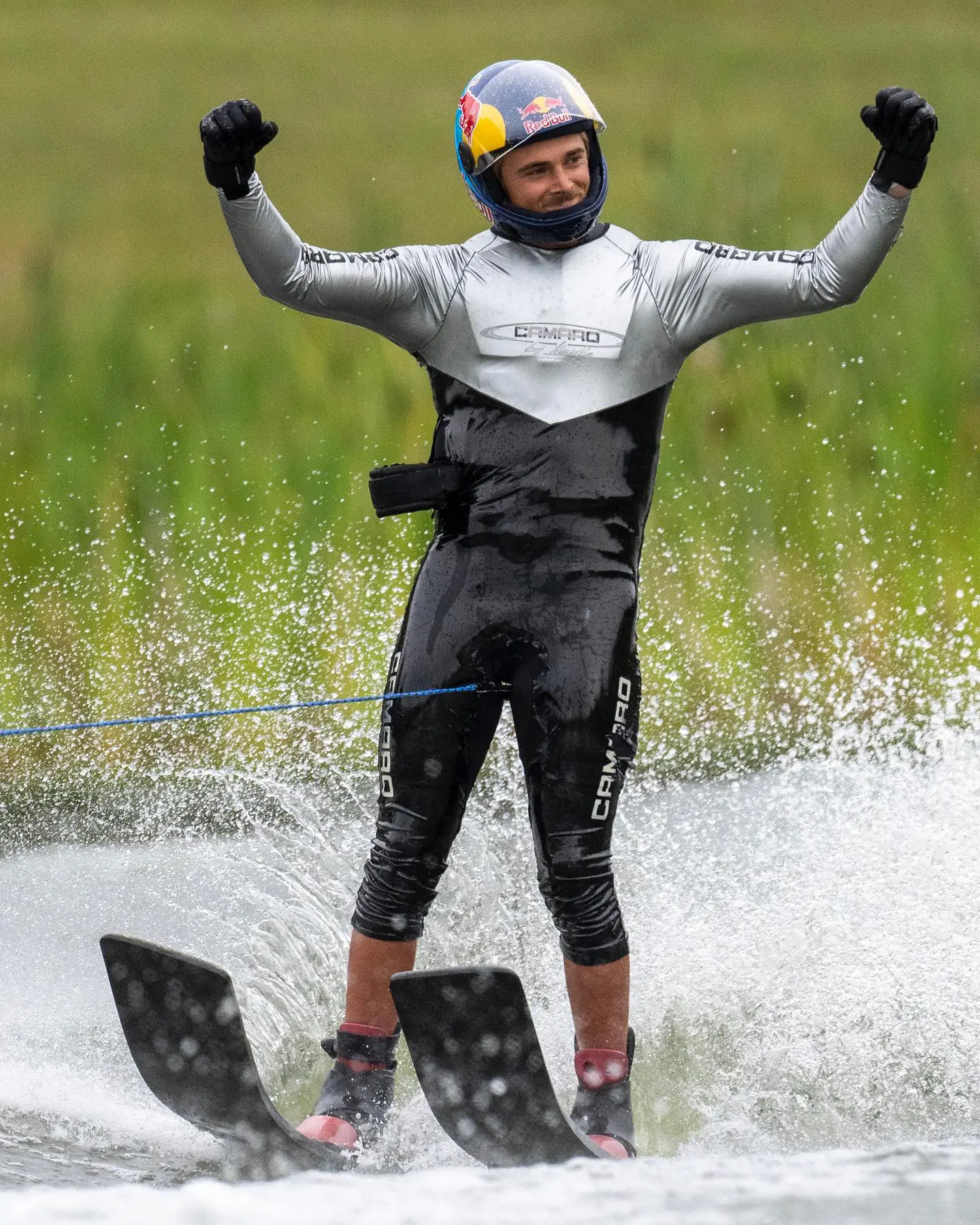 A man in black and white wetsuit riding water skis.