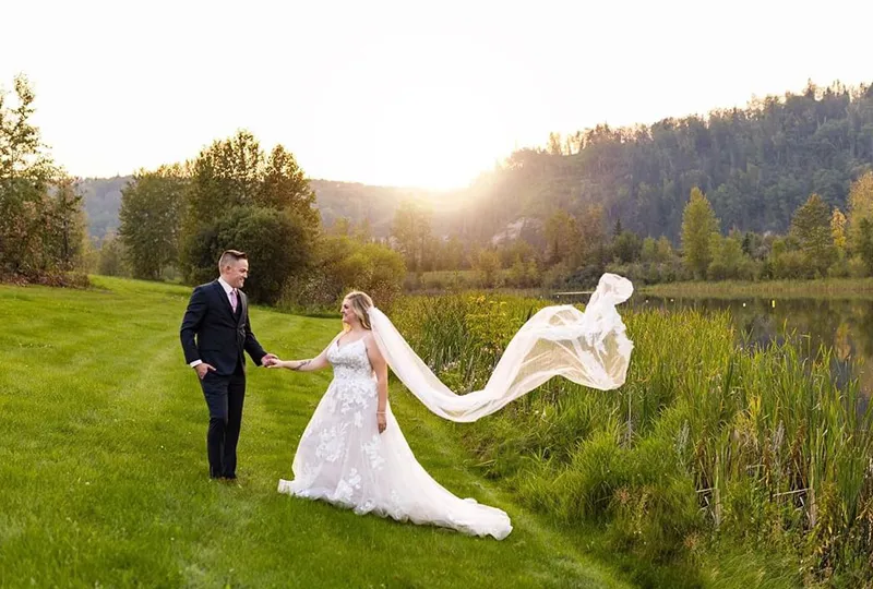 A bride and groom holding hands in the grass.