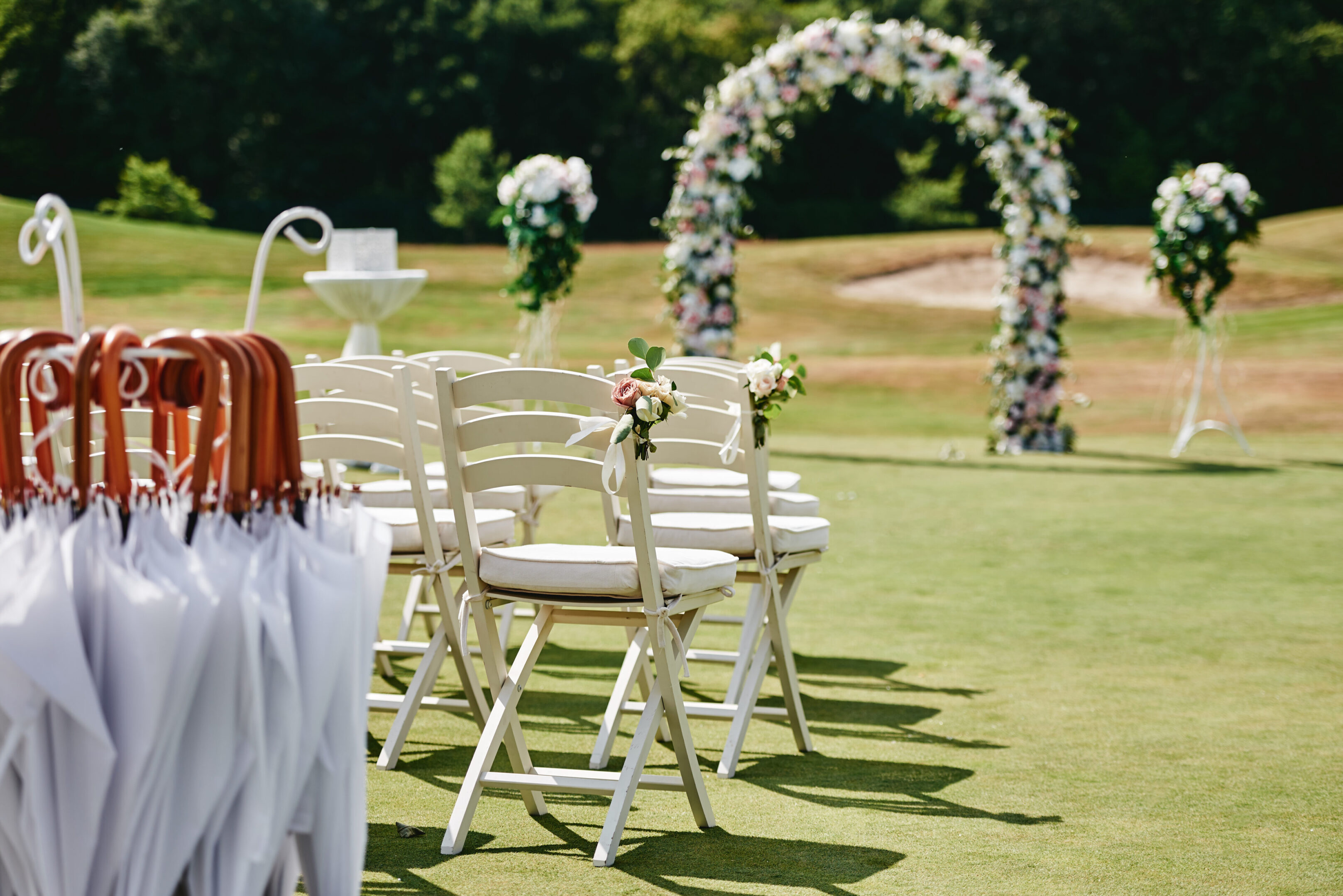 A wedding set up with white chairs and flowers.