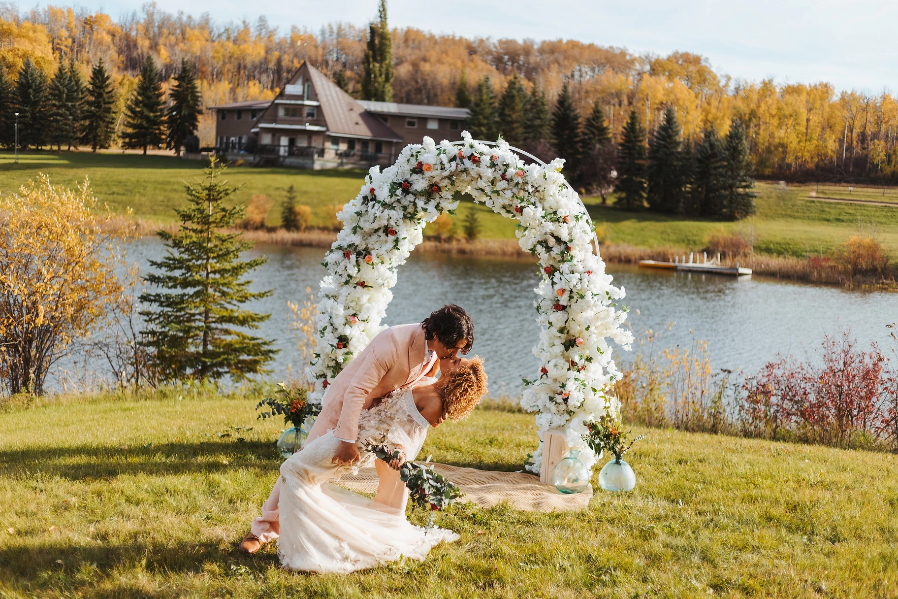 A couple kissing under an arch near the water.