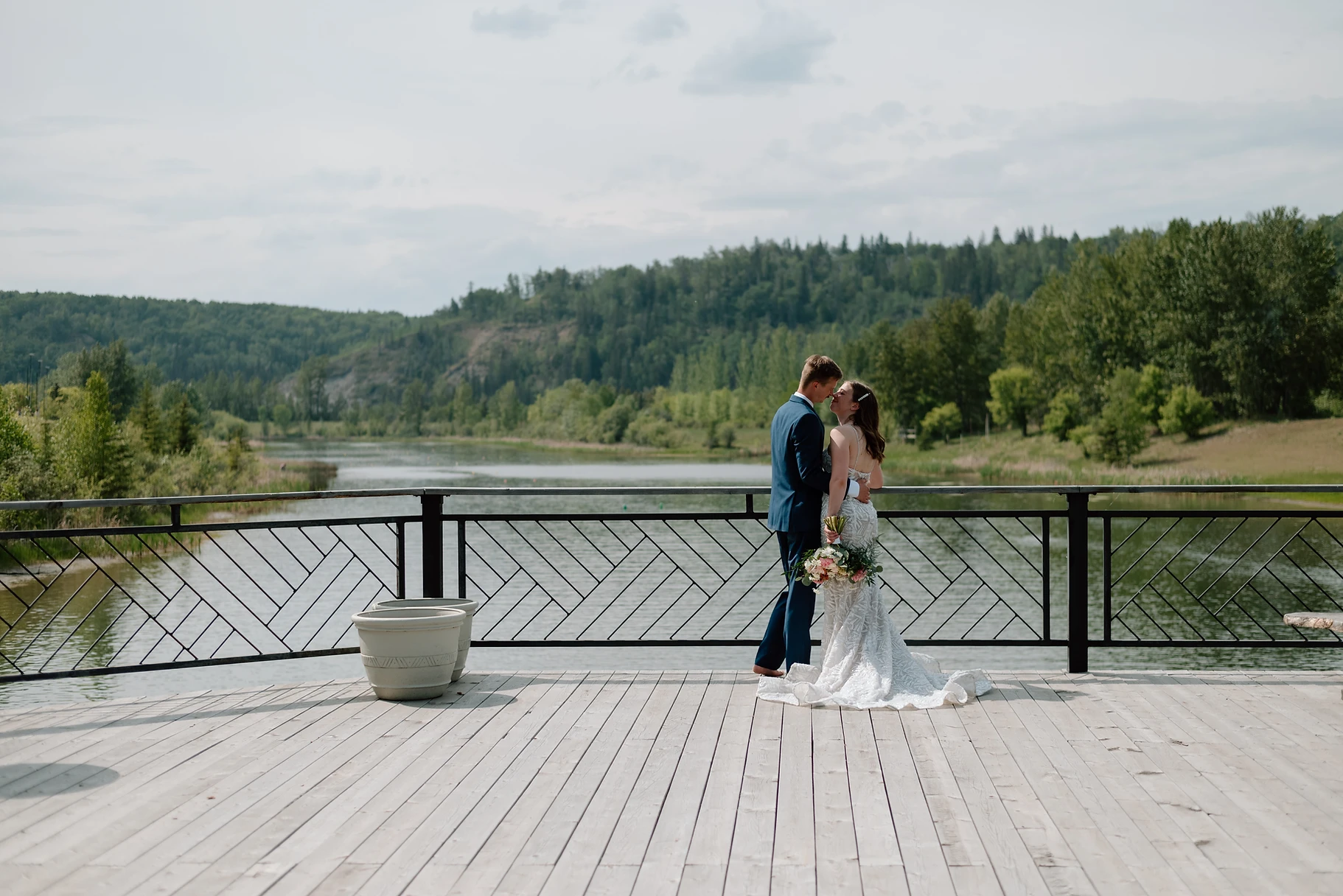 A bride and groom kissing on the side of a bridge.