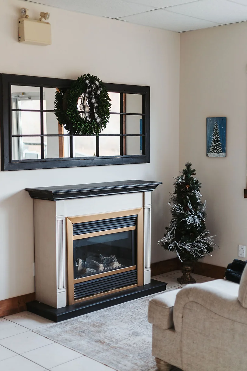 A fireplace with a mirror above it and a christmas wreath on the wall.